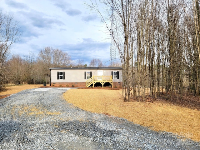 view of front facade with driveway, crawl space, stairs, and a deck