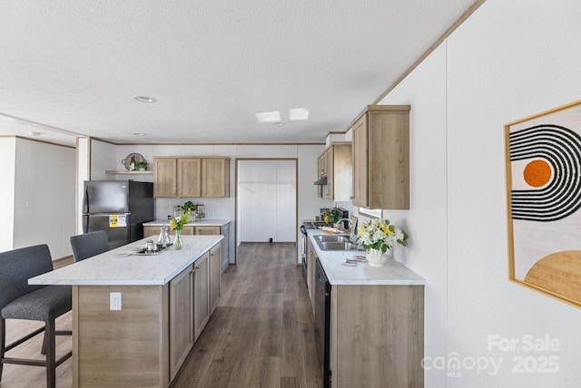 kitchen with a textured ceiling, a breakfast bar, a kitchen island, freestanding refrigerator, and dark wood-style floors