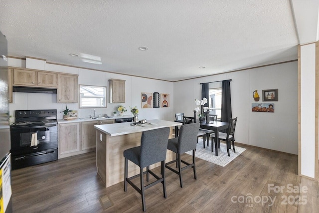 kitchen with dark wood-style floors, electric range, a breakfast bar area, and light countertops