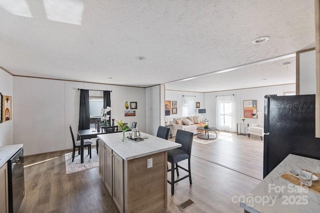 kitchen with dark wood finished floors, a breakfast bar, open floor plan, a center island, and black appliances