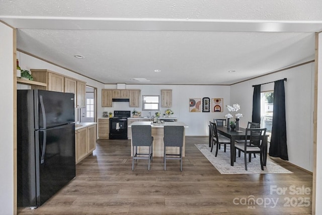 kitchen featuring dark wood-style floors, light countertops, a kitchen island, and black appliances