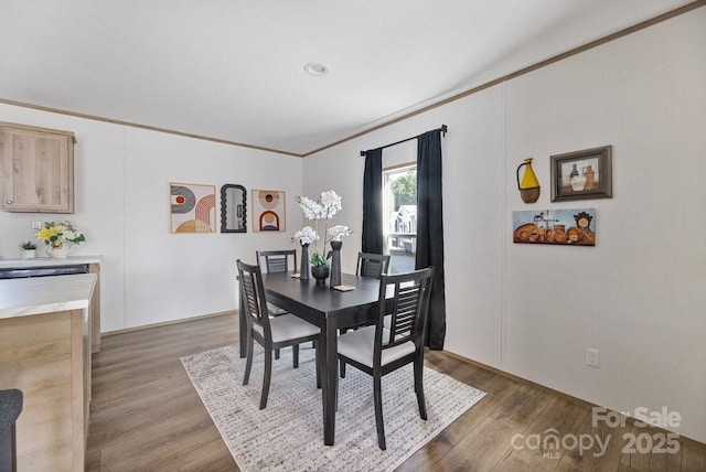 dining area featuring wood finished floors and crown molding