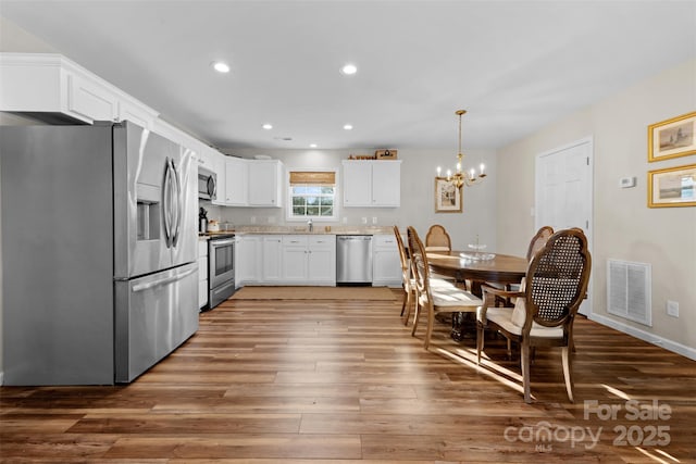 kitchen with visible vents, white cabinets, appliances with stainless steel finishes, light countertops, and pendant lighting