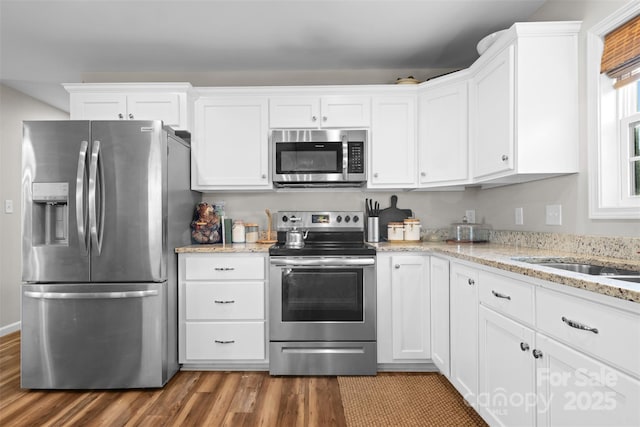 kitchen with appliances with stainless steel finishes, white cabinets, and light stone counters