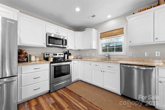 kitchen featuring stainless steel appliances, a sink, visible vents, white cabinets, and dark wood-style floors