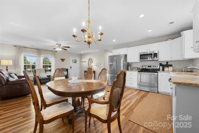 dining room with light wood-type flooring, ceiling fan with notable chandelier, visible vents, and recessed lighting