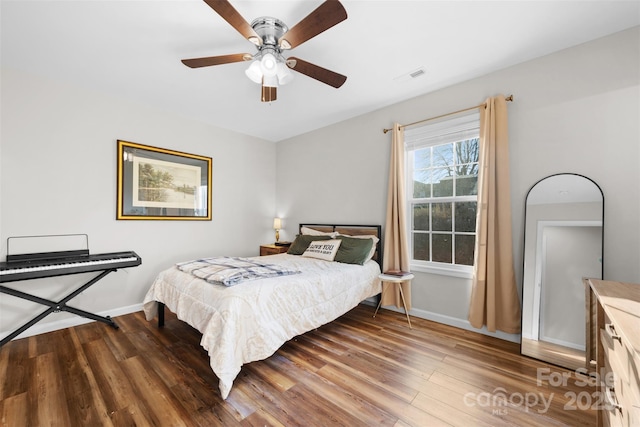 bedroom featuring dark wood-style floors, baseboards, visible vents, and ceiling fan