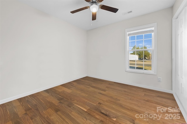 unfurnished room with visible vents, ceiling fan, baseboards, and wood finished floors