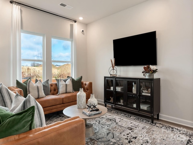 living area with visible vents, baseboards, and wood finished floors