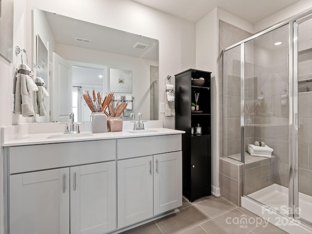 full bathroom featuring a stall shower, a sink, visible vents, and tile patterned floors