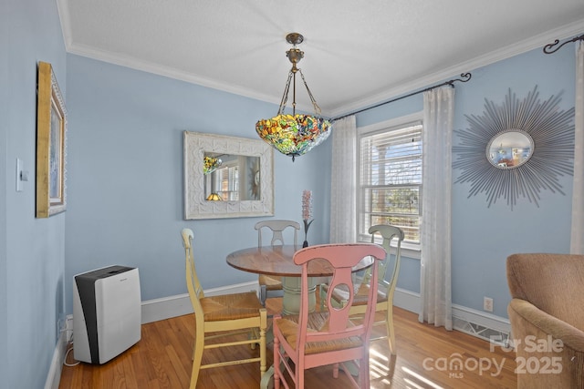 dining space featuring crown molding, baseboards, and wood finished floors