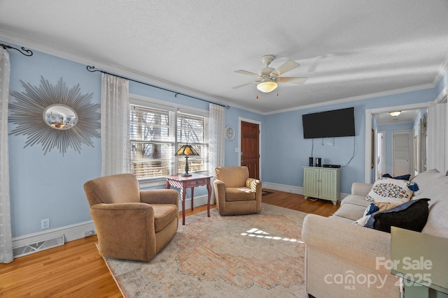 living area with a textured ceiling, ornamental molding, wood finished floors, and visible vents