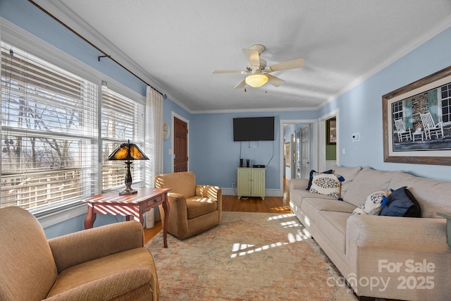 living area with a ceiling fan, baseboards, ornamental molding, and wood finished floors