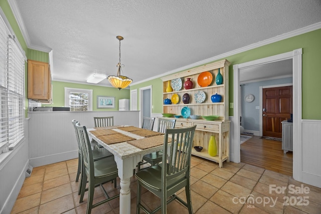 dining space with a wainscoted wall and ornamental molding