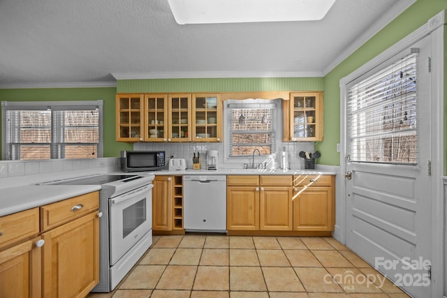 kitchen with light tile patterned floors, light countertops, glass insert cabinets, a sink, and white appliances