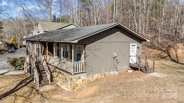 view of side of property with a shingled roof and a porch