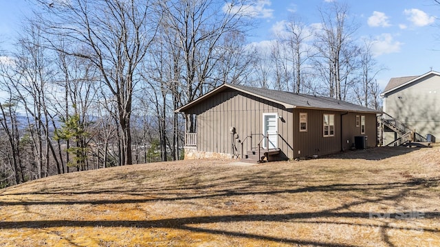 view of property exterior featuring board and batten siding, central AC, and a yard