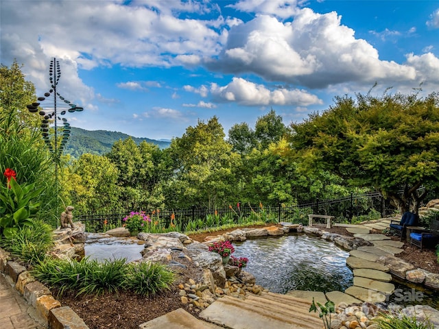 exterior space featuring a small pond, fence, and a mountain view