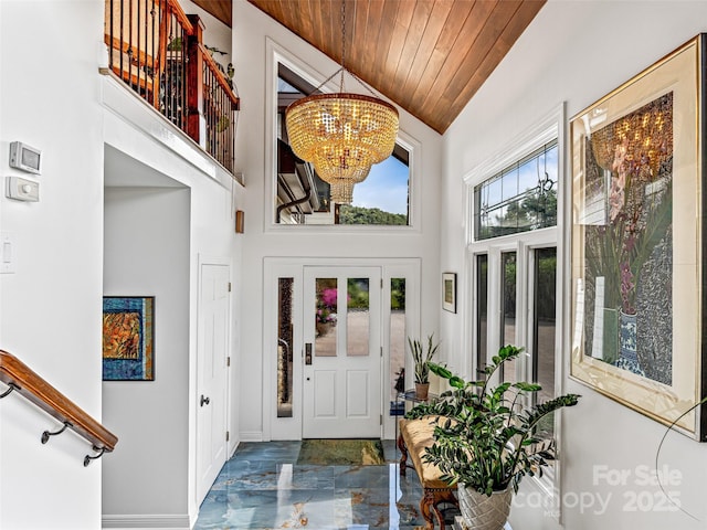 foyer with high vaulted ceiling, wood ceiling, a chandelier, and baseboards