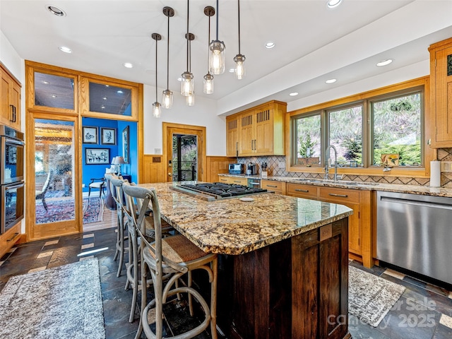 kitchen with a wainscoted wall, a kitchen island, glass insert cabinets, and stainless steel appliances