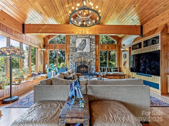 living room featuring wood walls, plenty of natural light, wood finished floors, and a stone fireplace