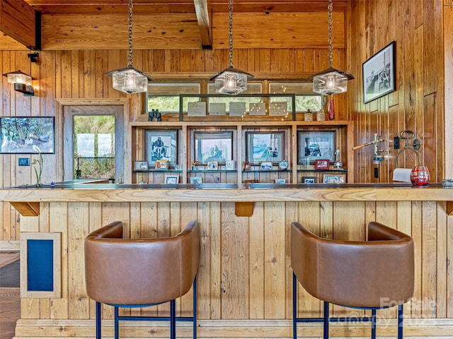 bar featuring wood walls, bar area, and beam ceiling