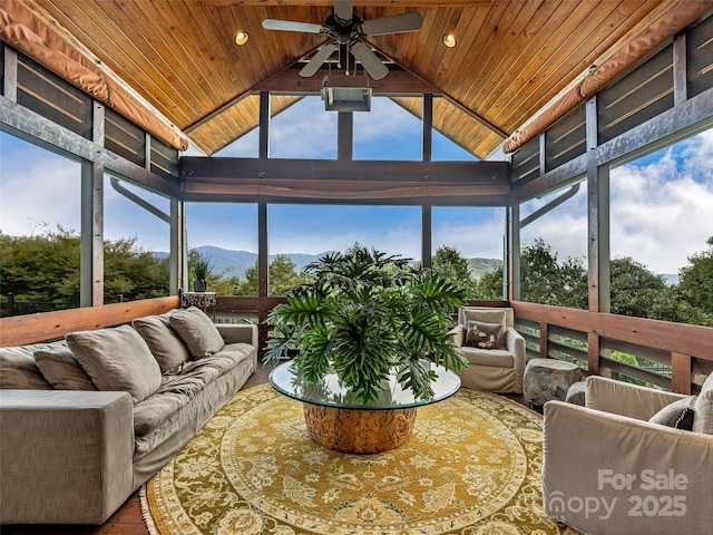 sunroom / solarium with vaulted ceiling, wood ceiling, a mountain view, and ceiling fan