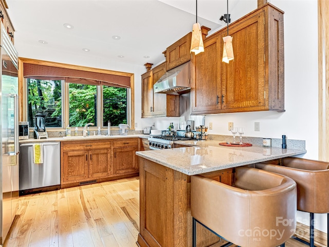 kitchen with a peninsula, stainless steel dishwasher, range, a kitchen bar, and decorative light fixtures