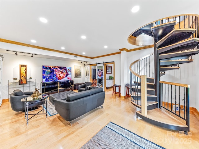 living area with a barn door, baseboards, stairs, light wood finished floors, and crown molding