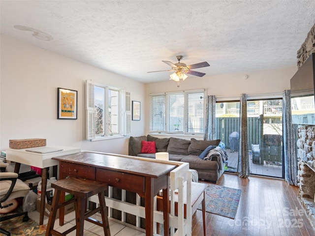 living area featuring a ceiling fan, wood-type flooring, and a textured ceiling