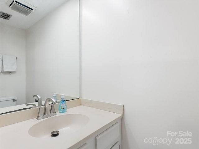 bathroom with toilet, visible vents, and vanity