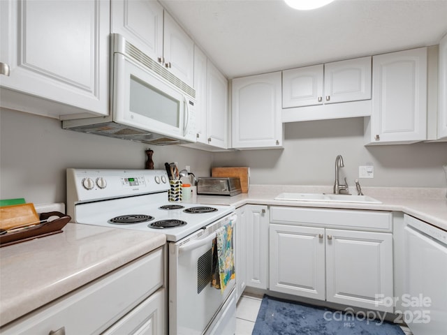 kitchen featuring white appliances, white cabinetry, light countertops, and a sink