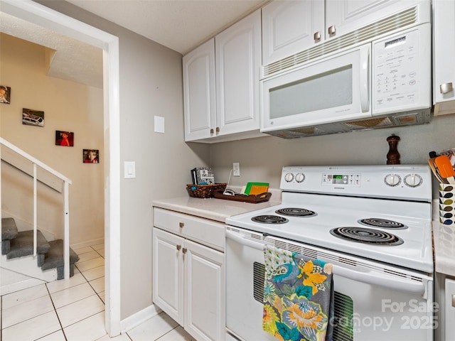 kitchen featuring light countertops, light tile patterned flooring, white cabinets, white appliances, and baseboards