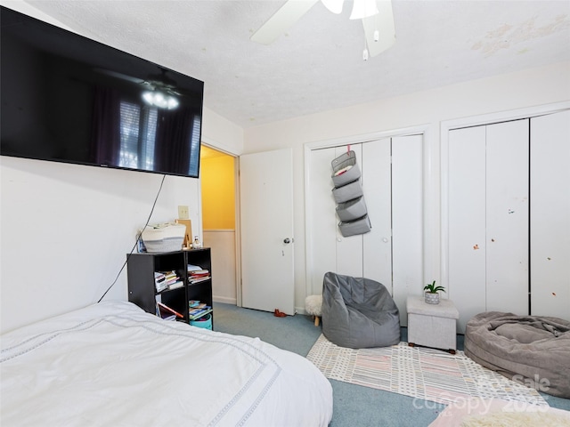 bedroom with ceiling fan, multiple closets, and light colored carpet