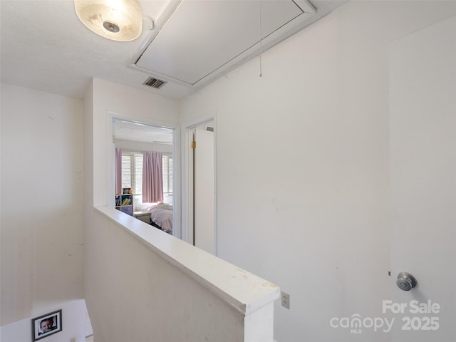 hallway featuring attic access and visible vents