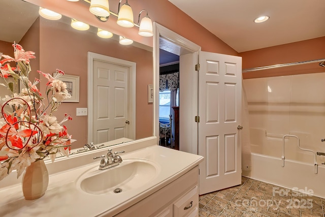 bathroom with stone finish flooring, shower / bathing tub combination, and vanity