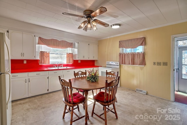 dining room featuring ornamental molding, visible vents, wood walls, and a ceiling fan