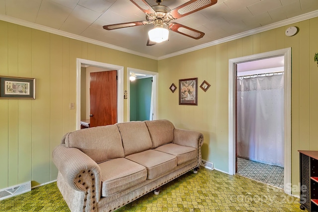 living area with baseboards, a ceiling fan, visible vents, and crown molding