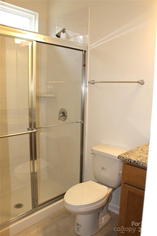 bathroom with a shower stall, toilet, and tile patterned floors