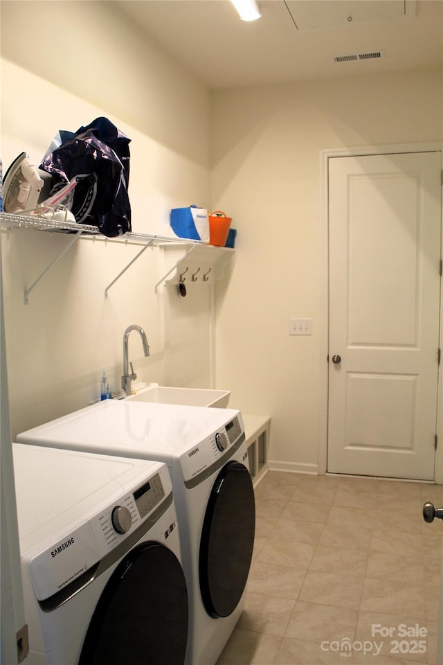 washroom featuring laundry area, washing machine and dryer, a sink, and visible vents