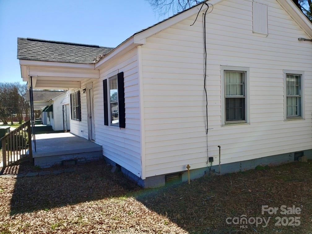 view of side of property featuring covered porch, a shingled roof, and crawl space