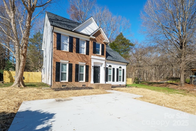 view of front of property with roof with shingles, brick siding, crawl space, and fence