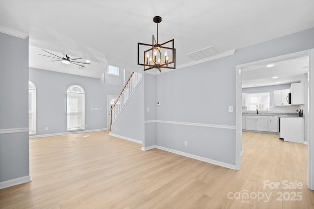 interior space with ceiling fan with notable chandelier, visible vents, baseboards, stairs, and light wood-style floors