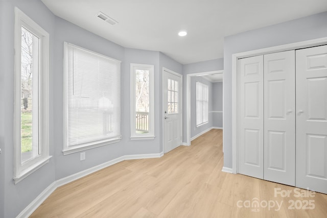 interior space featuring light wood finished floors, baseboards, and visible vents