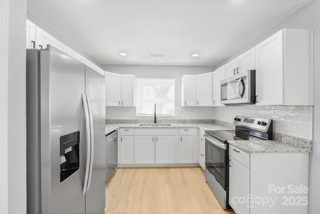 kitchen featuring stainless steel appliances, white cabinetry, and a sink