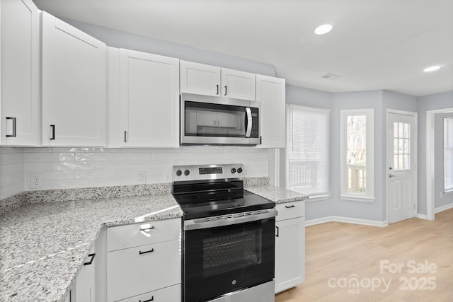 kitchen with stainless steel appliances, tasteful backsplash, light stone countertops, and white cabinets