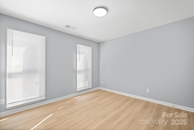 empty room with visible vents, baseboards, and wood finished floors