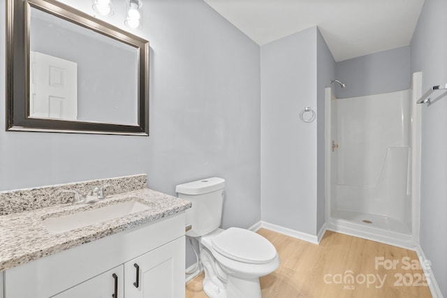 full bath featuring baseboards, toilet, wood finished floors, vanity, and a shower stall