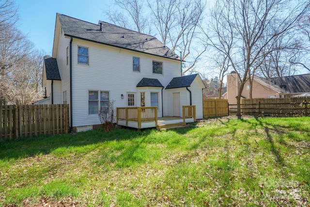 back of house featuring a fenced backyard, roof with shingles, a deck, and a yard