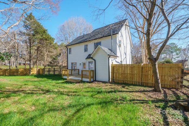 back of house featuring a deck, a lawn, and a fenced backyard